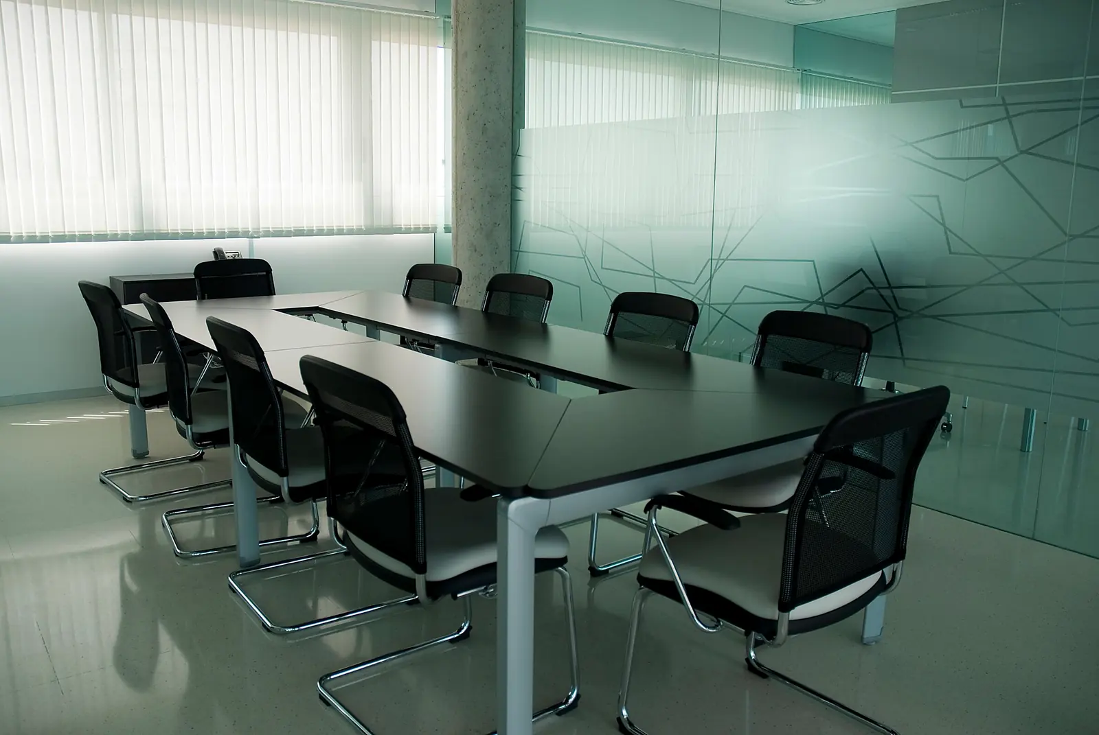 Sala de reunião com mesa longa e divisórias de vidro